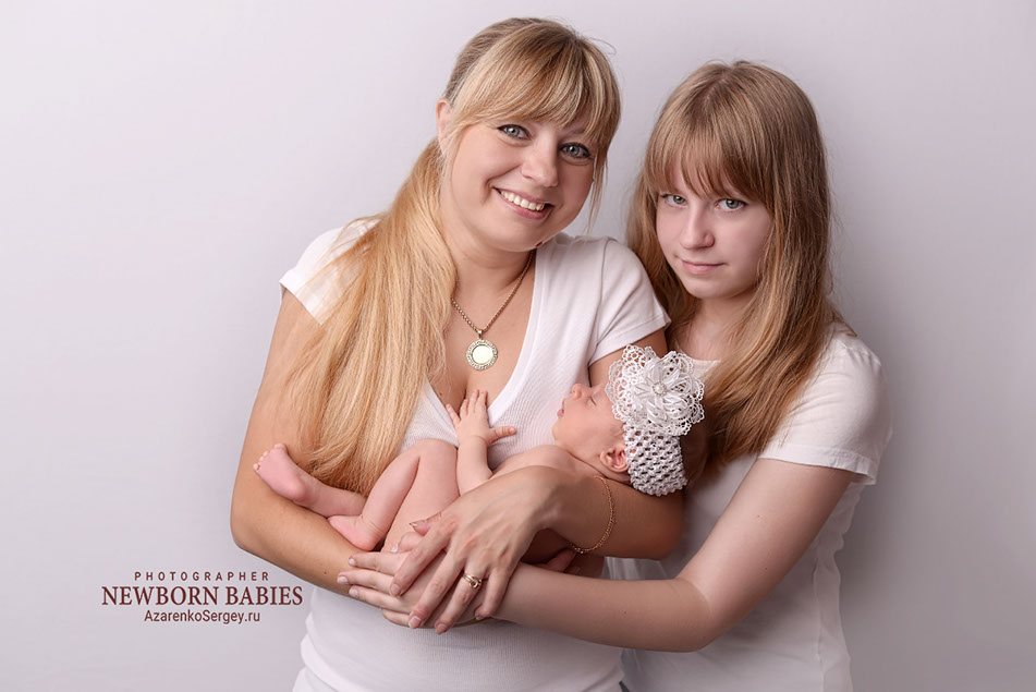 Новорожденная малышка в руках мамы и сестры. Семейный портрет.